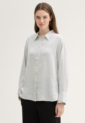 Light gray button-up shirt with a textured, crinkled fabric, collar, and long sleeves. Features a relaxed fit and visible buttons along the front.