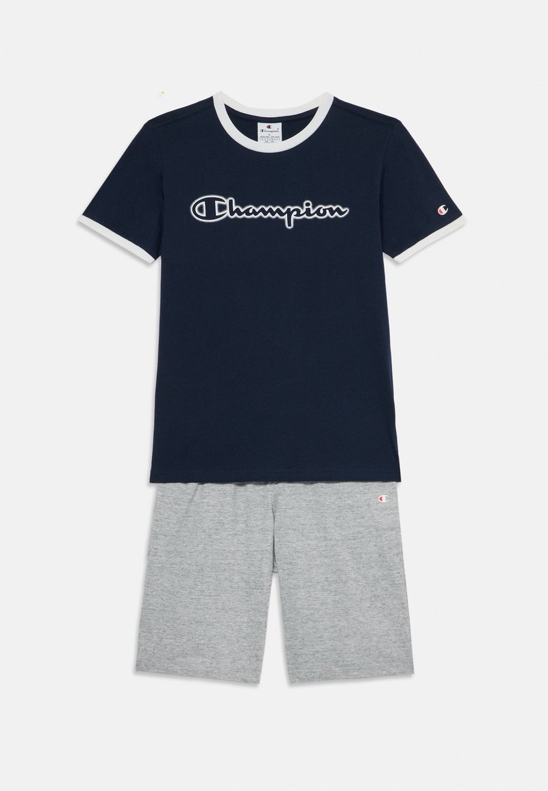 T-shirt azul-marinho de mangas curtas com colarinho branco e logótipo "Champion", combinado com calções cinzentos com um logótipo bordado na bainha.