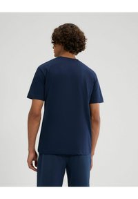 Camiseta de manga corta de color azul marino, hecha de algodón suave, con cuello redondo y un corte relajado, vista desde la parte posterior.