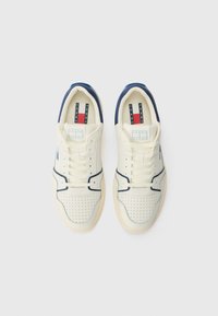 Baskets en toile crème avec des accents bleu marine, une boîte à orteils perforée et des lacets blancs. Comprend une étiquette de logo à l'intérieur de la languette et une semelle en caoutchouc.