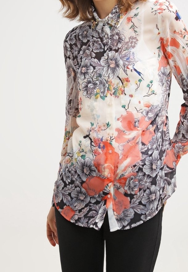 Blouse transparente à manches longues avec un imprimé floral en noir, blanc et corail, dotée d'une fermeture à boutons sur le devant et d'un col pointu.