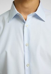 Camicia a righe azzurro chiaro con colletto classico, patta con tre bottoni e texture della stoffa liscia.