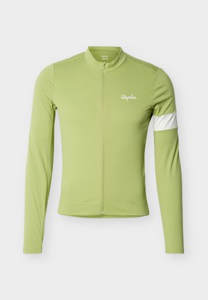 Jasnozielona koszulka kolarska z długim rękawem, pełny zamek błyskawiczny z przodu, biała opaska na lewej ręce i logo „Rapha” na lewej piersi.