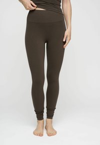 Leggings marroni con vita alta, caratterizzati da una texture liscia e una vestibilità su misura. Tessuto elasticizzato, progettato per comfort e flessibilità.