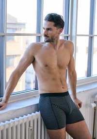 Boxers en noir et blanc à rayures, avec une taille élastique douce, présentant une coupe ajustée et une texture de tissu lisse.