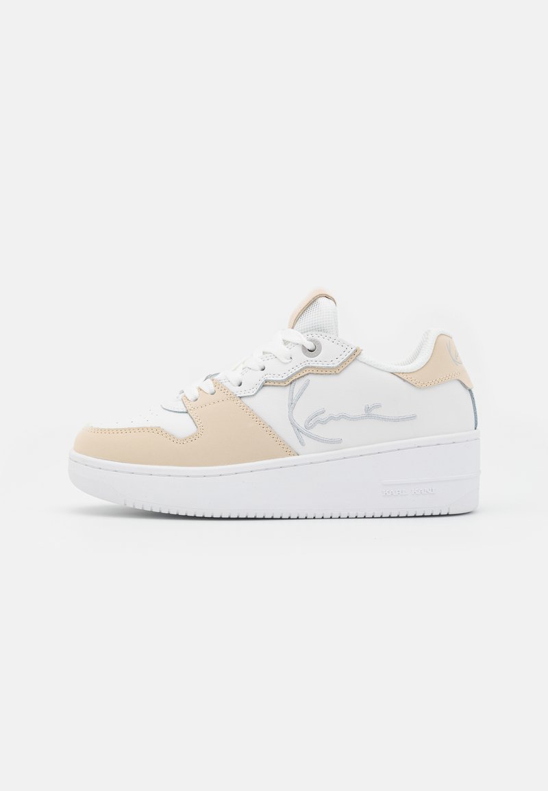 Hvit og beige sneakers i skinn og tekstil, med en teksturert overdel, gummimellomsåle og brodert signaturdetalj på siden.
