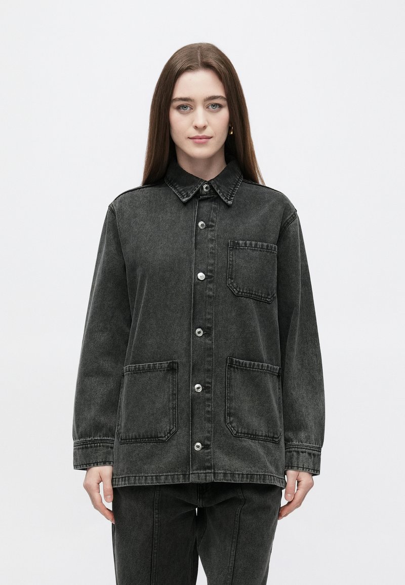 Temno siva jeans jakna z ovratnikom, gumbi spredaj in dvema obližnima žepoma. Ima sproščen kroj in mat teksturo.