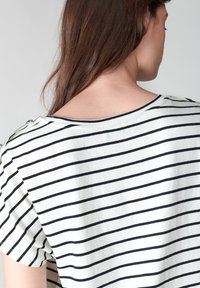 Top de rayas con franjas horizontales en blanco y negro, tejido suave, escote ancho y detalle de botones en el hombro.