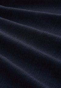 Námořnická textilie s jemnou strukturou, vykazující měkký povrch. Materiál se pod světlem zdá hladký a mírně odrazový.