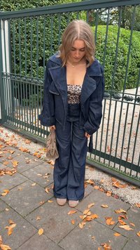 Denim kombinacija z veliko jakno in razširjenimi hlačami, obema v temno modri barvi. Pod njo je leopardji potisk, v kombinaciji s svetlo bež čevlji.