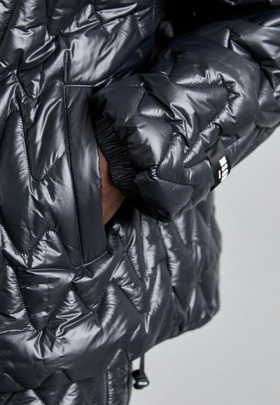 Gefütterte Jacke aus glänzendem schwarzem Material mit Zickzacknähten, verstellbaren Manschetten und einer Seitentasche. Ausgestattet mit elastischem Saum und Branding-Details.