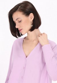 Ljuslila cardigan med V-hals, knäppning fram och långa ärmar. Slät textur med minimala sömdetaljer.