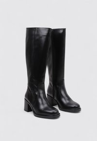 Botas de cuero negro hasta la rodilla con puntera cuadrada, tacón cuadrado y cierre lateral con cremallera. Textura suave con detalles de costura mínimos.