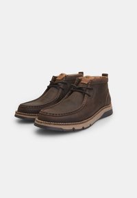 Bottines en cuir marron avec une finition texturée, accents beiges contrastants, détails cousus et semelle en caoutchouc flexible.