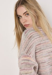 Multicolored knitted sweater featuring a soft texture with pink, gray, and beige stripes, wide sleeves, and a ribbed hem.