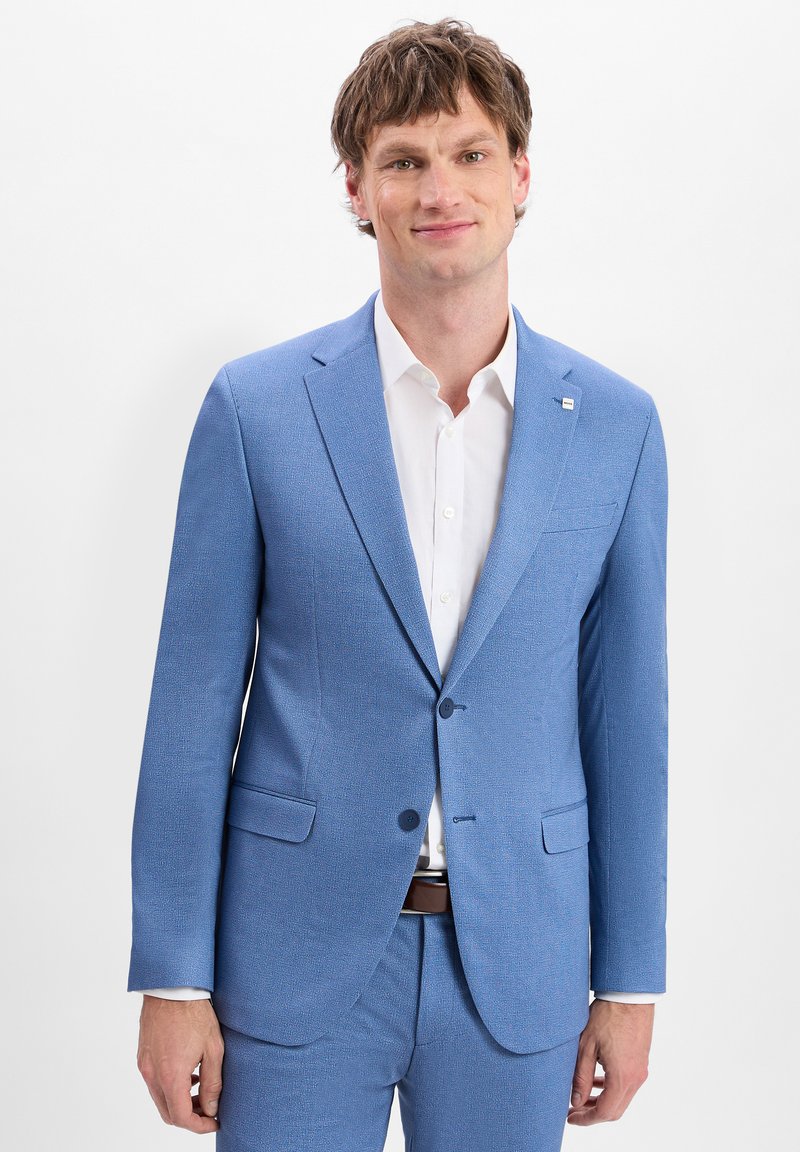 Hellblauer, strukturierten Anzug mit einreihigem Design, zwei Knöpfen und Seitentaschen, kombiniert mit einem weißen Hemd und einem braunen Gürtel.