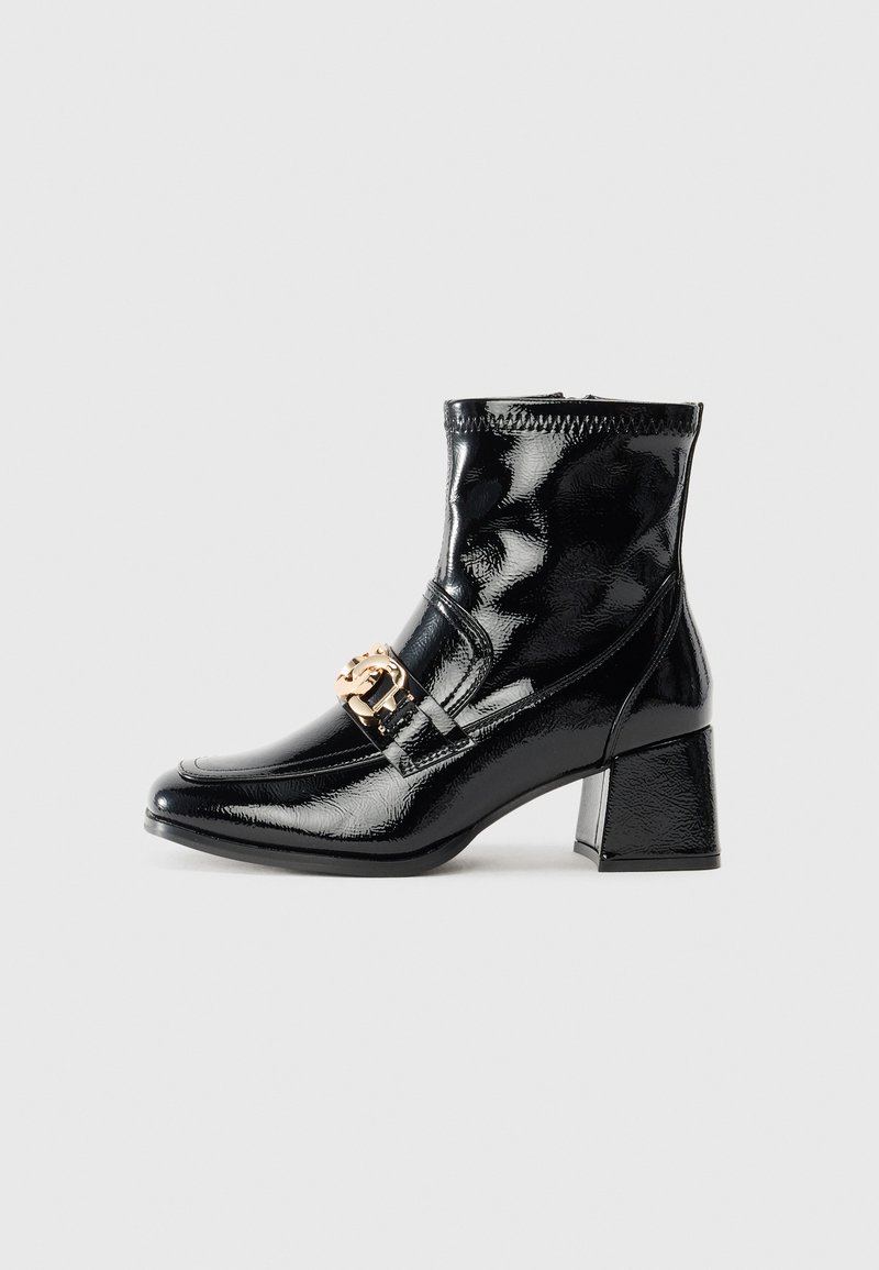 Svart patentlær ankle boot med firkantet tå og hæl. Har et gullfarget spenne og sømdetaljer langs overdelen.