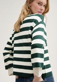 Grün-weiß gestreifter Pullover mit lockerer Passform, Rundhalsausschnitt und Dreiviertelärmeln. Strukturierte Strickware mit sichtbaren Nähten.