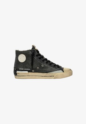 Sneaker nera alta con lacci neri, suola beige, occhielli metallici, toppa rotonda con logo e scritta "CRIME LONDON" sul lato.