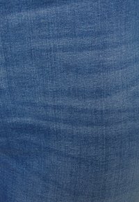 Denimtyg i medelblått med en subtil textur; har klassiskt vävmönster och lätta variationer i färgen.