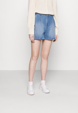 Lichtblauwe denim shorts met een elastische taille, een relaxte pasvorm en een rafelige zoom. Gecombineerd met een lange mouwen, gestippeld overhemd en witte sneakers.