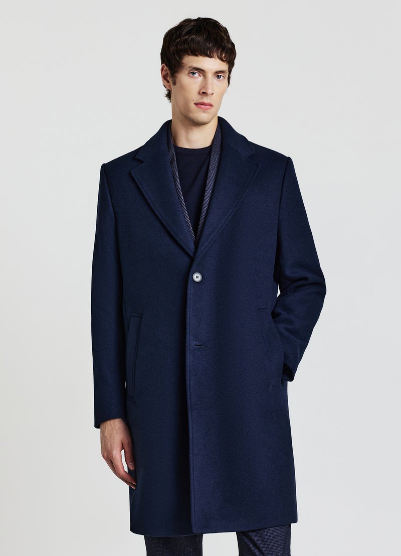Cappotto in lana blu navy con rever a lancia, chiusura con un bottone singolo e due tasche laterali, con una texture liscia e una vestibilità sartoriale.