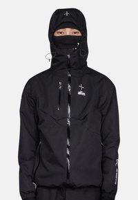 Veste noire imperméable avec poches zippées, une capuche ajustée, des cordons de serrage réglables et un logo sur la poitrine et la manche.