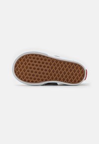 Podeszwa sneakersa z wzorem plastra miodu, wykonana z brązowej gumy, z białymi krawędziami. Posiada czerwony akcent na pięcie.