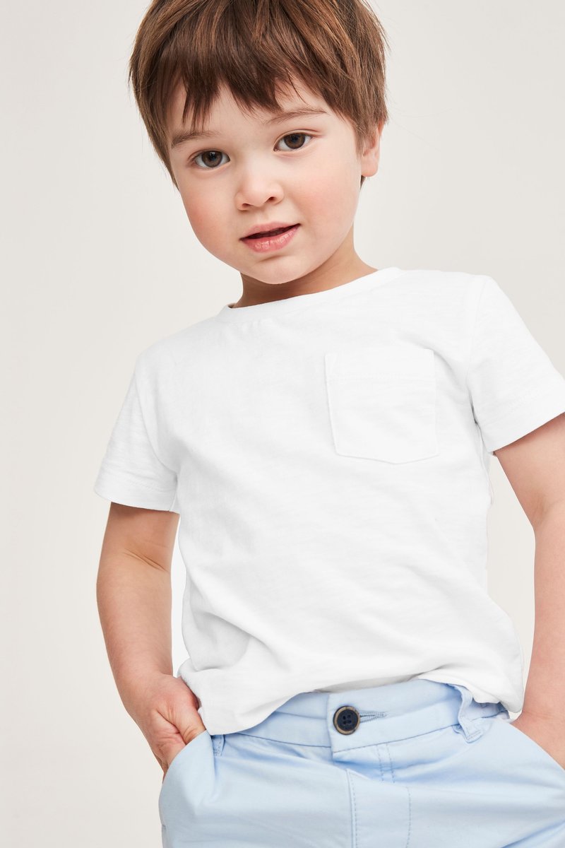 Camiseta blanca de manga corta con un bolsillo frontal, combinada con pantalones azul claro que tienen un botón negro. Textura suave y lisa.
