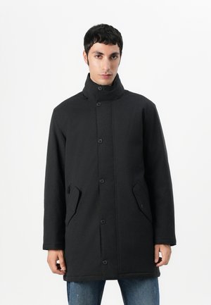 Zwarte jas met een hoge kraag, voorzien van knoopsluiting, zijzakken en een rechte snit. Gladde textuur met minimale details.