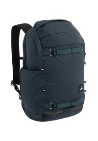 Dunkelblauer Rucksack mit schlankem, abgerundetem Design. Verfügt über einen oberen Reißverschluss, eine Seitentasche, verstellbare Träger und kontrastierende Riemen mit Schnallen.