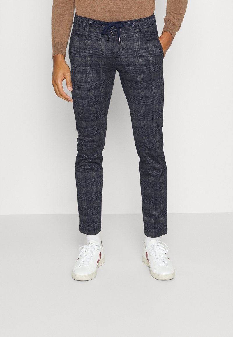 Navy geruite broek met een slim fit, gemaakt van een zachte stof. Voorzien van een trekkoord in de taille en voorzakken. Gemaakt in combinatie met witte sneakers.
