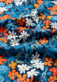 Daugiaspalvė medžiaga su gėlių raštu, kurio fone yra tamsiai mėlyna spalva; ji apima baltas, oranžines ir mėlynas gėles su žaliais akcentais. Minkšta struktūra.