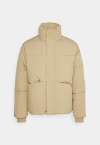 Beige padded jacket featuring a high collar, vertical front closure, and ribbed cuffs. Smooth texture with minimalist design and no visible hardware.