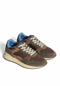 Baskets en daim marron avec une languette en mesh, des lacets gris, un panneau de talon bleu clair et une semelle en caoutchouc beige avec un motif de texture antidérapant.