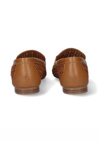 Zapatos marrones de piel sin cordones con laterales trenzados, tacón plano y acabado suave. La parte trasera tiene una forma redondeada y detalles de costura mínimos.