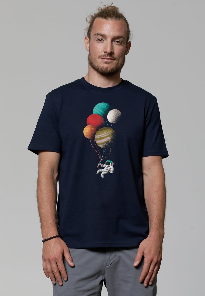 T-shirt en coton bleu marine avec un motif d'astronaute tenant des ballons de planète multicolores. Manches courtes, col rond.