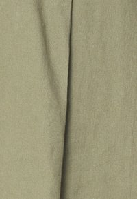 Olivgrüner Stoff mit einer strukturierten Oberfläche, der in der Mitte einen ausgeprägten Faltenwurf aufweist und eine weiche, gewebte Optik hat.