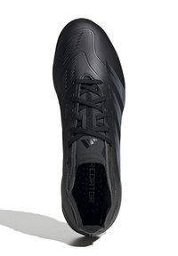 Black athletic shoe with a textured surface, featuring a round toe, lace closure, and subtle stripes on the sides. Interior reads "PREDATOR."