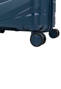 Maleta azul con ruedas, con una superficie texturizada, que presenta un diseño elegante y dos ruedas negras giratorias para una fácil maniobrabilidad.