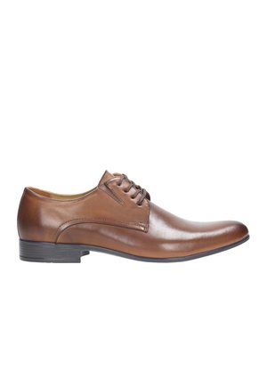 Chaussure habillée en cuir marron avec une finition polie, bout rond, fermeture à lacets et semelle en caoutchouc à profil bas. Texture lisse et couture minimale.