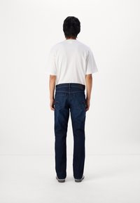 Jeans din denim albastru cu o croială dreaptă, având cinci buzunare și detalii de cusătură subtile. Asortate cu un tricou alb simplu.