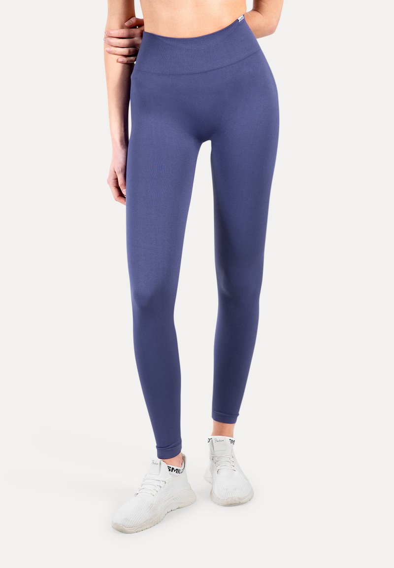 Leggings de cintura alta en un tejido azul oscuro sólido con textura suave, combinados con zapatillas deportivas blancas con detalles negros.