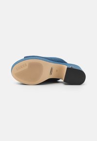 Suola di scarpa in tessuto blu con grip in gomma testurizzata, soletta beige con il marchio "GUESS" e la taglia "37" impressa di lato.