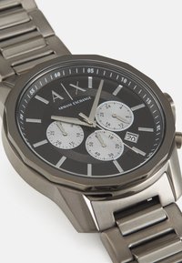 Ρολόι Armani Exchange με μαύρο καντράν, ασημί λεπτομέρειες, τρία υποκαντράν και βραχιόλι από ανοξείδωτο χάλυβα; σχέδιο οκταγωνικής κάσας.