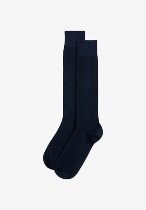 Marineblaue knielange Socken aus einem glatten, dehnbaren Stoff mit einem verstärkten oberen Rand und geschlossenem Zehenbereich. Keine sichtbaren Muster oder Hardware.