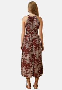 Vestido marrón sin mangas con un estampado de hojas, cintura ajustada y falda fluida. La tela texturizada y un detalle de escote en forma de lágrima completan el look.