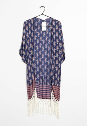 Niebieskie kimono z otwartym przodem, ozdobione małymi kwiatowymi nadrukami, czerwonym wzorzystym obrzeżem i białymi frędzlami, wiszące na czarnym wieszaku z białą metką.