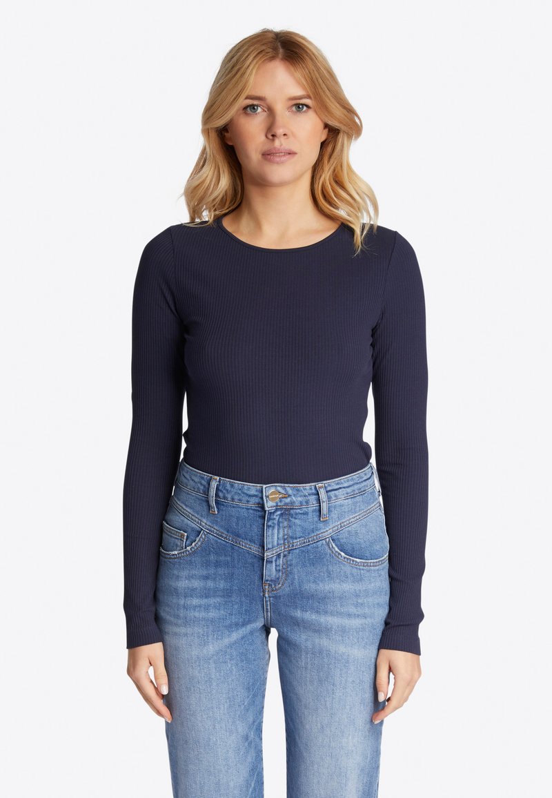 Top a maniche lunghe in maglia color navy, scollatura tonda, abbinato a jeans dritti leggeri blu chiaro con tasche frontali e dettagli di cucitura sottili.