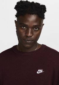 Bordeaux strikket sweater med rund hals, med et lille hvidt Nike-logo på brystet og struktureret stof.